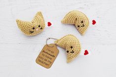 three crocheted keychains with tags attached to them on a white surface