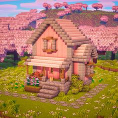 a small pink house sitting on top of a lush green field next to trees and flowers