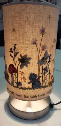 a lamp that is on top of a table with flowers and plants painted on it