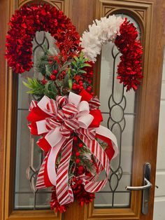 a red and white christmas wreath on a front door with flowers in the center,