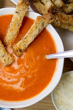 a bowl of tomato soup with bread sticks sticking out of it