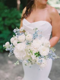 a bride holding a bouquet of white and blue flowers