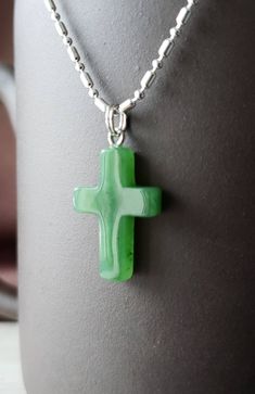 Genuine nephrite jade cross pendant from British Columbia, Canada. The color is a beautiful translucent green. Comes with a plated jump ring. Jade brings harmony and contentment to the wearer. In Asian cultures, Jade is revered as the good luck stone which can bring happiness, wealth, and friendship. Option to purchase heavy solid 925 sterling silver chain necklace. 22mm x 14mm Green Cross Necklace For Gift, Green Spiritual Cross Pendant Jewelry, Green Cross Pendant Necklace As Gift, Handmade Healing Cross Jewelry, Green Spiritual Necklace As Gift, Spiritual Green Necklace For Gift, Handmade Green Cross Jewelry, Cross Shaped Natural Stones Jewelry For Gift, Necklace Christian