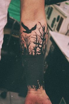 a person with a bird tattoo on their arm and the other hand is holding something