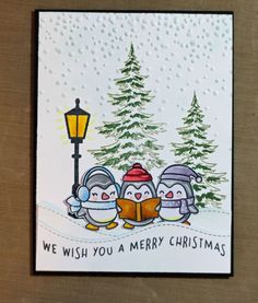 a christmas card with penguins reading a book in front of a snowy tree and street light