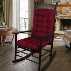 a red rocking chair sitting in front of a fire place