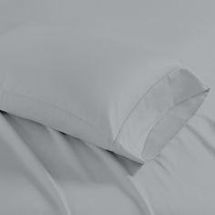 a close up view of a bed with white sheets and pillows