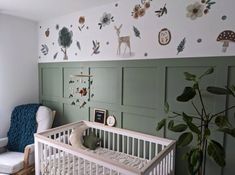 a baby's room decorated in green and white with deer wall decals on the walls