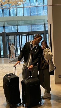 a man and woman standing next to each other with their luggage in front of them