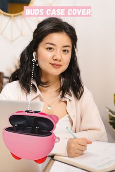 a woman sitting at a desk with a laptop and earbuds in her case