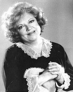 an old black and white photo of a woman with her hands on her chest smiling