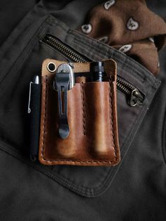 a leather wallet with two pens and a pocket knife