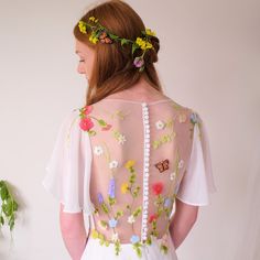 a woman in a white dress with flowers on her back