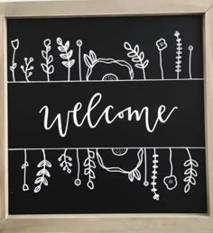 a chalkboard with the words welcome written in white ink on it and an image of plants