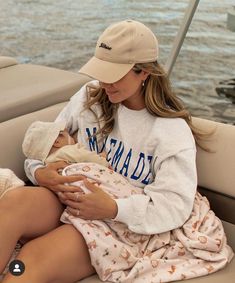 a woman holding a baby in her arms while sitting on the back of a boat