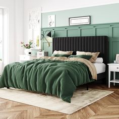 a bed with green sheets and pillows on top of it in a room that has wood floors