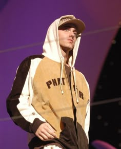 a man in a hoodie is standing on stage with his hands in his pockets