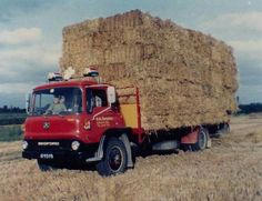 an old red truck hauling hay in a field