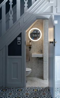 an open door leading to a bathroom with a sink and toilet under the stairs in a house