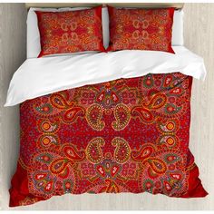 a bed with red and orange bedspread on top of it