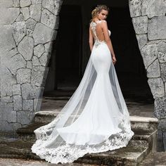 a woman in a wedding dress is standing on some steps with her back to the camera