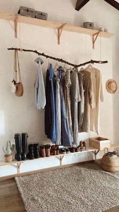 a room filled with lots of clothes hanging on a wall next to a rug and wooden shelves