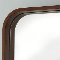 a mirror that is on the wall with a wooden frame around it's edge