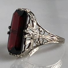 Details: Stunning Edwardian Period garnet and 14K white gold filigree ring! The stone measures 14.5mm by 7mm, and the is 4.6mm above the finger at the highest point on the ring. The filigree is beautiful on this ring, and is in lovely shape. This is a stunning ring--you will not be disappointed! Please ask all necessary questions prior to placing an order. Measurements: The size is 4 1/2 US and can be sized for a fee. Condition: The overall all condition of this ring is very good. Antique Ruby Ring With Filigree For Anniversary, Vintage Ruby Ring With Filigree For Formal Events, Classic Engraved Ruby Ring For Formal Occasions, Victorian Filigree Ring Stamped 14k For Formal Occasions, Antique 14k Gold Filigree Ring For Formal Occasions, Victorian Ruby Ring With Intricate Design For Formal Events, Victorian Engraved Filigree Ring For Formal Occasions, Vintage Filigree Ring With Gemstone For Formal Events, Ornate Ruby Ring With Filigree