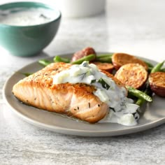 a plate with salmon, potatoes and green beans next to a bowl of ranch dressing