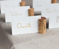 wine cork place cards on a table with white paper and gold lettering that says valene, charlotte