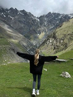 a woman standing on top of a lush green hillside