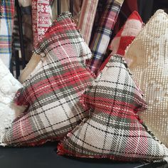 two decorative pillows sitting next to each other on a table in front of clothing racks