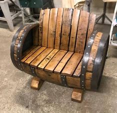 a chair made out of wooden barrels sitting on top of a cement floor in a room