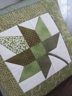 a green and white patchwork quilt on top of a wooden table