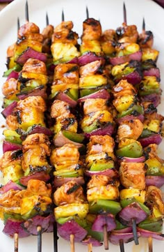 several skewers of food sitting on a white plate with purple cloth around it