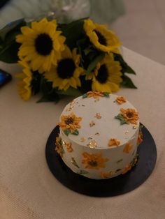 a white cake with sunflowers on it and a cell phone next to it