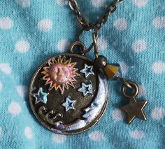 "A cute necklace to pop on when you want to add a little celestial style to your outfit! A little sun and moon pendant is accented with touches of violet and golden-pink and tiny stars are detailed in light turquoise blue! A Swarovski crystal bicone bead dangles at one side along with a little star charm, adding sparks of purple light! Just choose your favorite length and make it yours! Antiqued Gold-plated Charm 3/4\" round, Antiqued Gold-plated Necklace w/ Lobster Clasp 18\"-28\" MORE ARTFUL I Unique Necklaces Pendant, Whimsigoth Trinkets, Beaded Star Necklace, Aesthetic Stuff To Buy, Sun And Moon Pendant, Celestial Style, Bead Dangles, Star And Moon Necklace, Whimsical Accessories