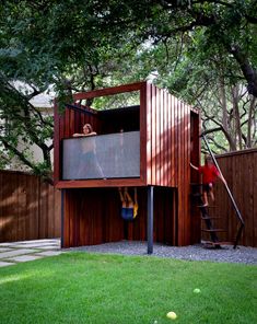 two people climbing up the side of a wooden structure in a yard with green grass and trees