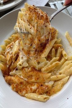 a white plate topped with pasta and chicken covered in sauce next to another plate full of food