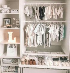 a white closet filled with lots of baby clothes and shoes next to a night stand