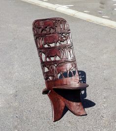 a wooden chair that is sitting on the ground in the middle of the street,