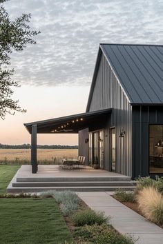 a house with a covered patio in the middle of a grassy area next to a field