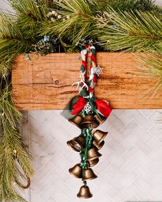 a bunch of bells hanging from the side of a wooden beam with christmas decorations on it