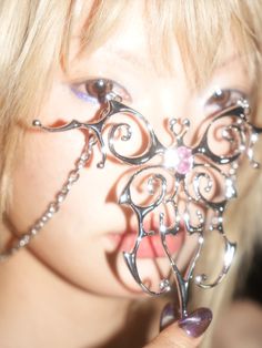 a close up of a person holding a piece of metal in front of their face