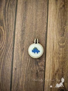 a small cross stitch ornament sitting on top of a wooden table