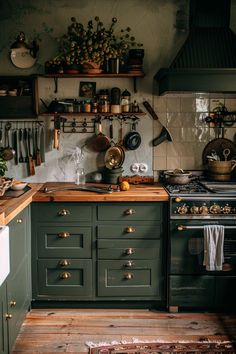 Cozy vintage kitchen featuring sage green cabinets, hardwood floors, and eclectic decor. Perfect blend of rustic charm and functionality. Forest Green Kitchen Decor, Green Black And Wood Kitchen, Fall Inspired Kitchen, Green Kitchen Tile Floor, Goblincore Interior Design, Green Kitchen Cabinets Diy, Dark Green Pantry, Light Academia Aesthetic Kitchen, Cottage Home Inspiration