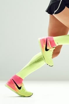 the legs and feet of a female tennis player in neon green socks with pink accents