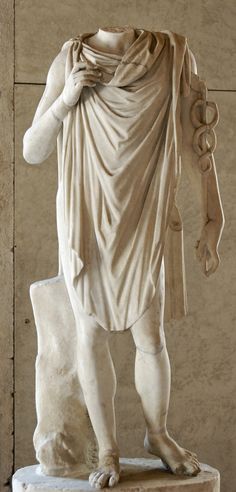 a statue of a man standing on top of a white pedestal next to a wall