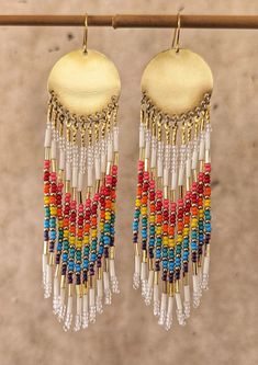 two pairs of earrings with multicolored beads hanging from a wooden hook on a clothes line