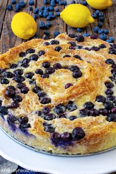 a blueberry pie on a white plate with lemons and blueberries around it